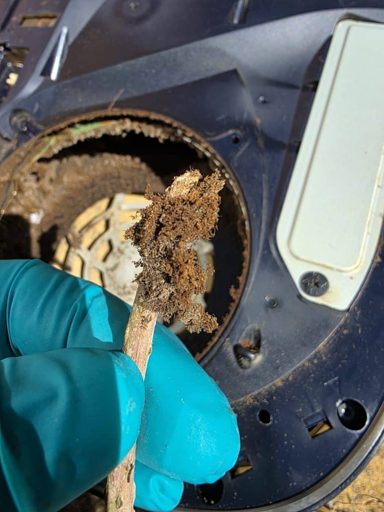 Gloved hand removing a clump of compacted dust from inside a PS5 fan housing