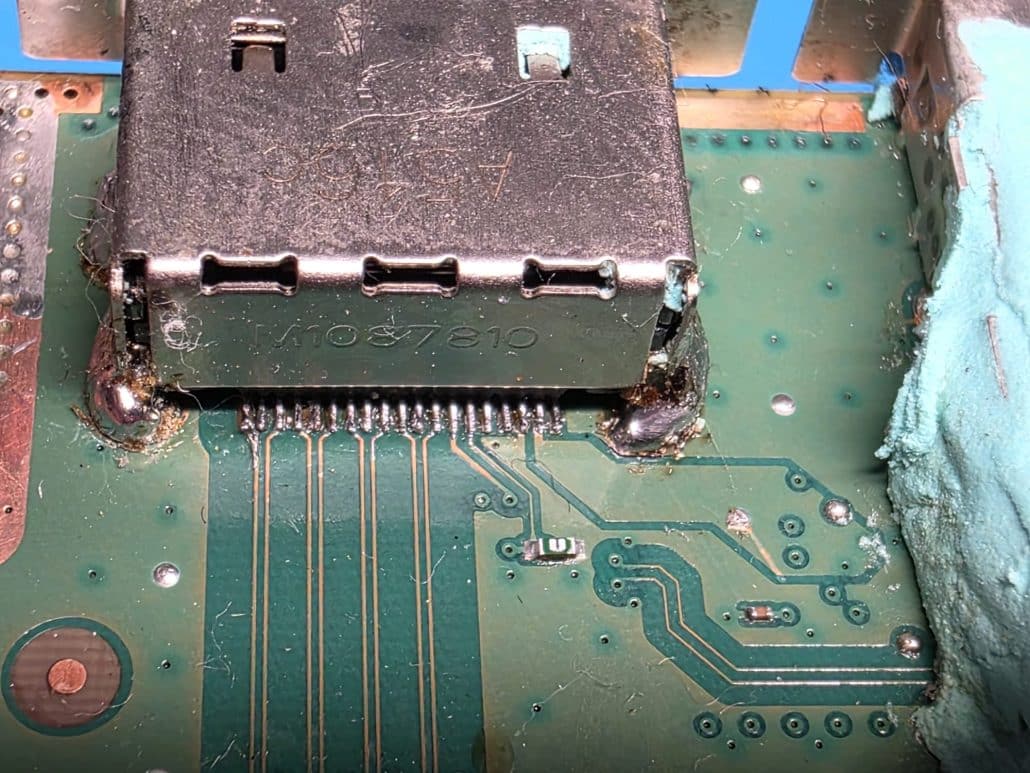 Xbox console HDMI port on the motherboard with excess solder and flux residue around the connector