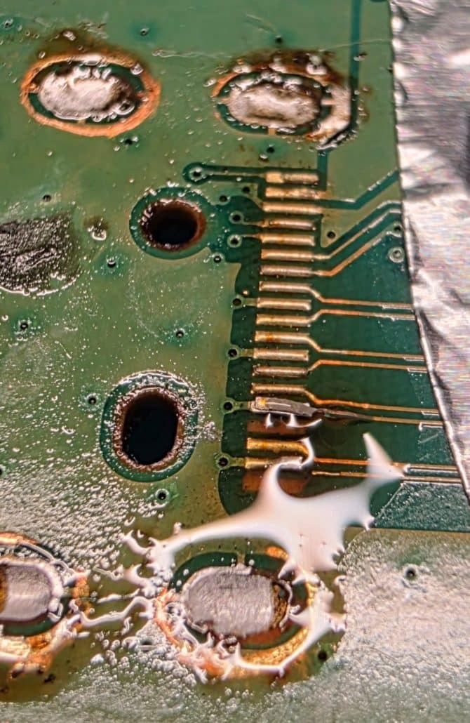 Xbox motherboard with damaged HDMI solder pads and copper tracks after the port was removed