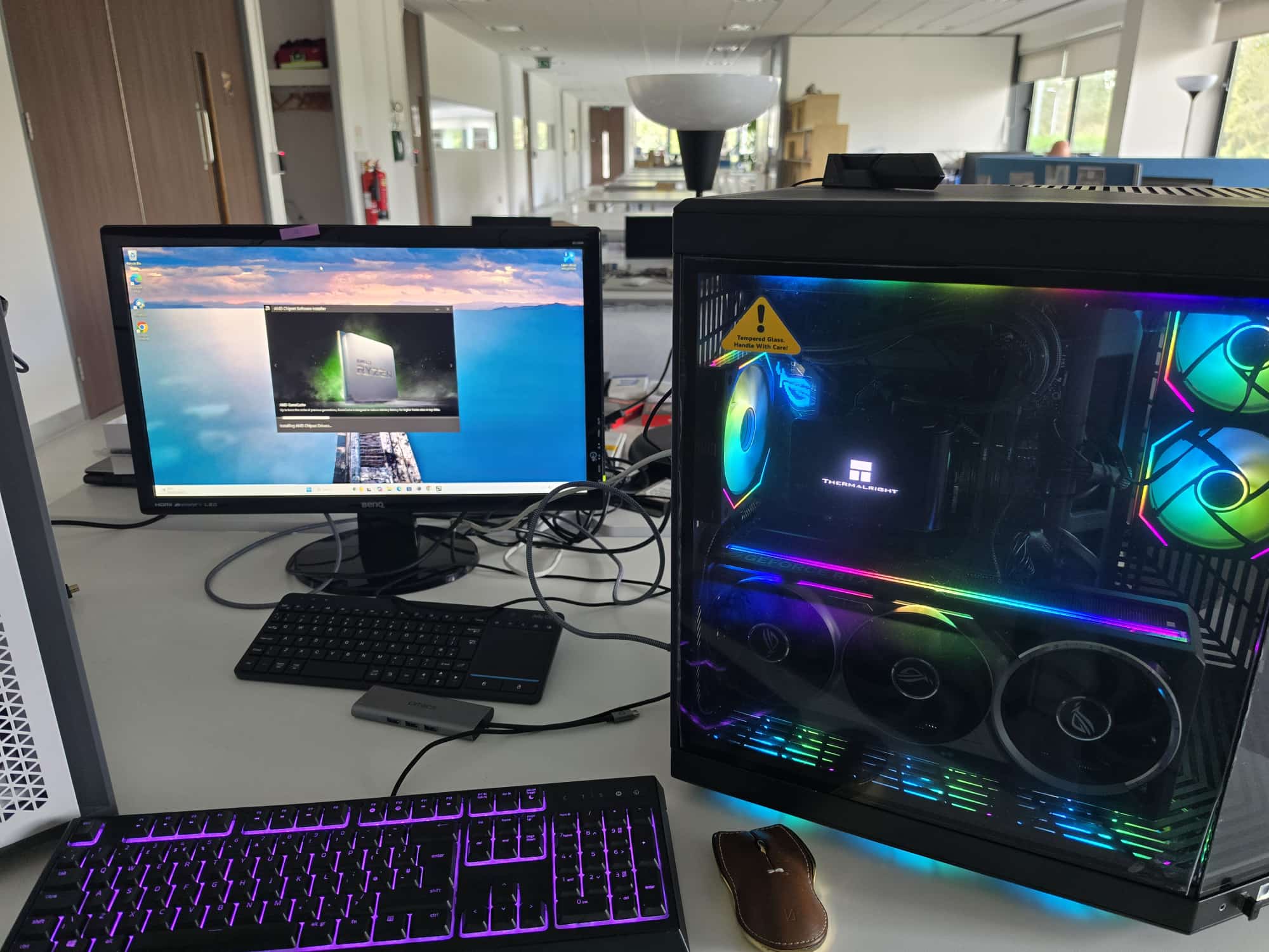 Custom built gaming PC with RGB lighting and a glass side panel next to a monitor and keyboard