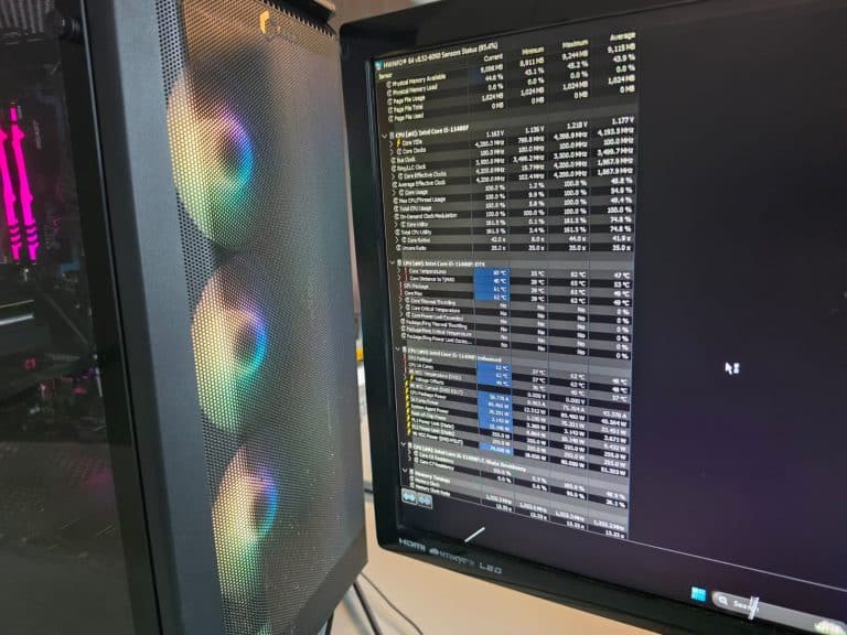 Custom PC with RGB fans next to a monitor showing system temperatures