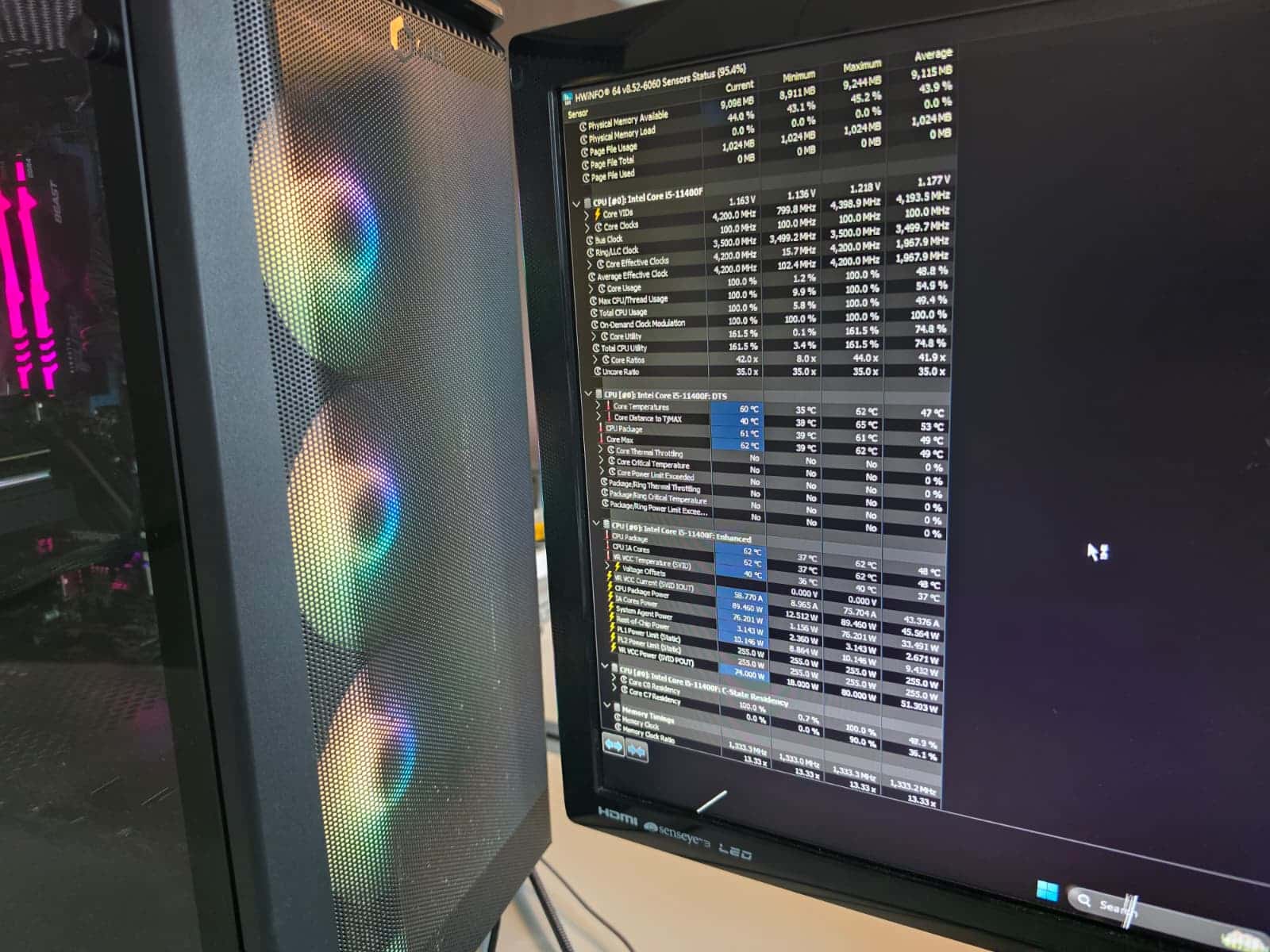Custom PC with RGB fans next to a monitor showing system temperatures
