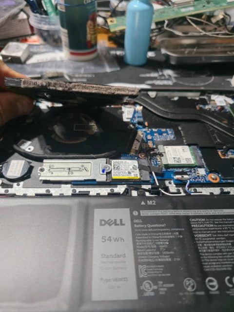 Hand holding up a Dell laptop heatsink whose fins are blocked with dust