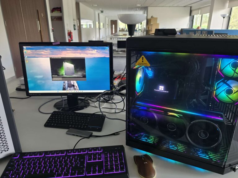 Custom built gaming PC with RGB lighting and a glass side panel next to a monitor and keyboard