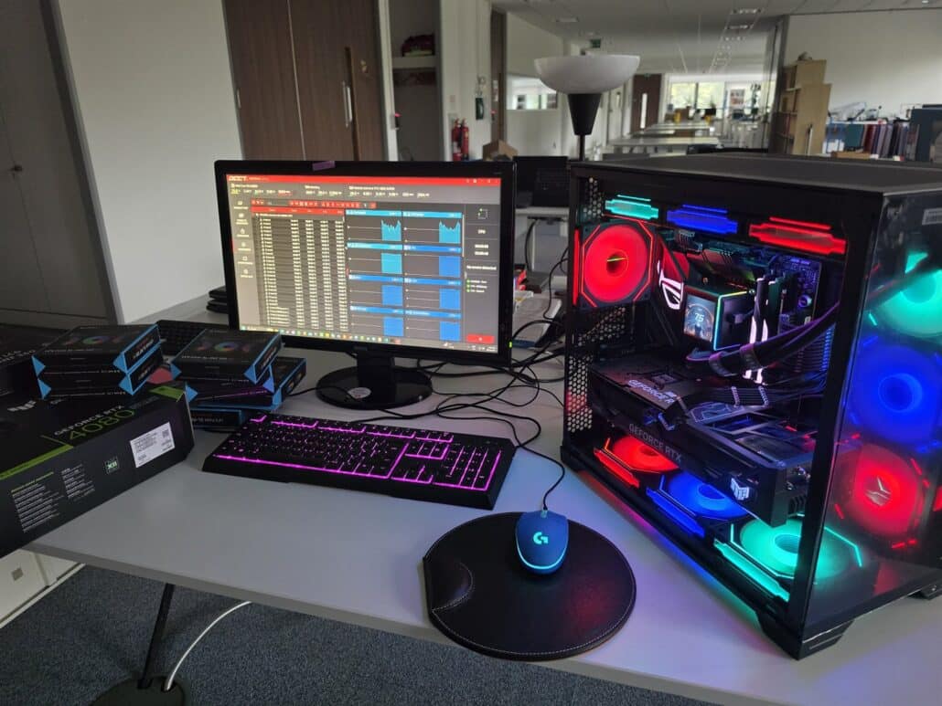 The finished custom PC on our test bench running the OCCT stability test, with the fan and graphics card boxes next to the monitor
