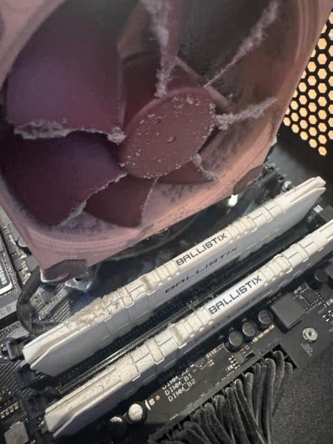 Large CPU cooler fan with fluffy dust stuck on the blades above the memory modules