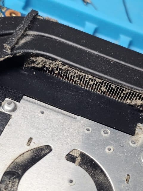 Close-up of laptop heatsink fins packed with grey dust