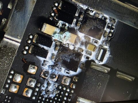 Dried drink residue crystallised around chips on a MacBook logic board, seen under the microscope