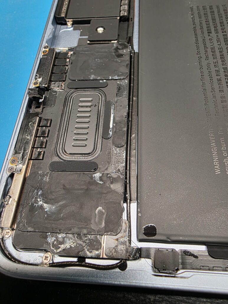 Dried liquid residue on the speaker, battery edge and trackpad cable inside a MacBook Air after a spill