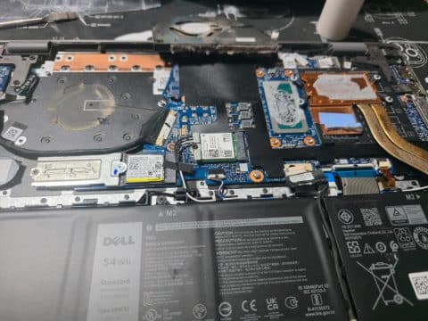 Inside a Dell laptop with the heatsink lifted, showing dried paste on the copper plates