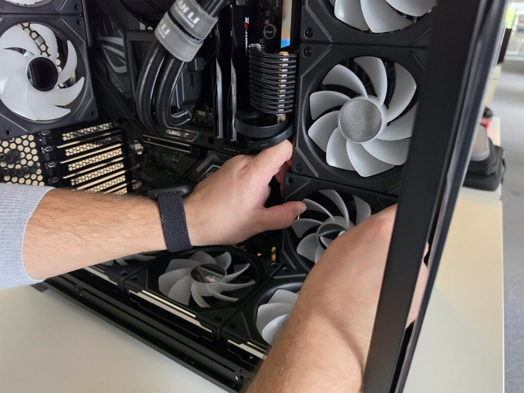 Fitting Lian Li reverse-blade fans by hand inside the Lian Li O11 Vision case during a custom PC build