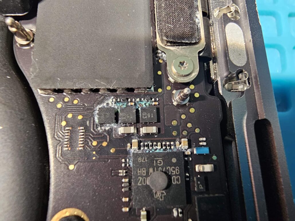 White and green corrosion around components on a MacBook Air logic board after a liquid spillage