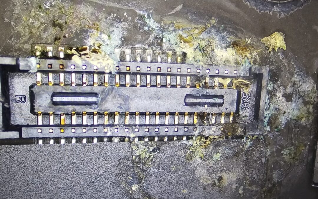 Corroded board connector on a MacBook logic board after a liquid spillage, seen under the microscope