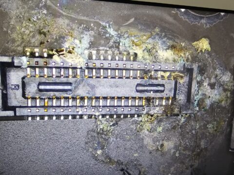 Corroded board connector on a MacBook logic board after a liquid spillage, seen under the microscope