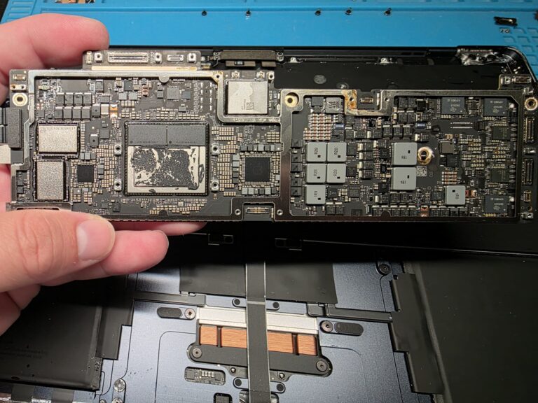 Our engineer holding a MacBook logic board removed for liquid spillage cleaning and repair