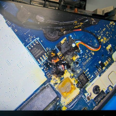 Liquid residue and corrosion on a laptop motherboard before repair