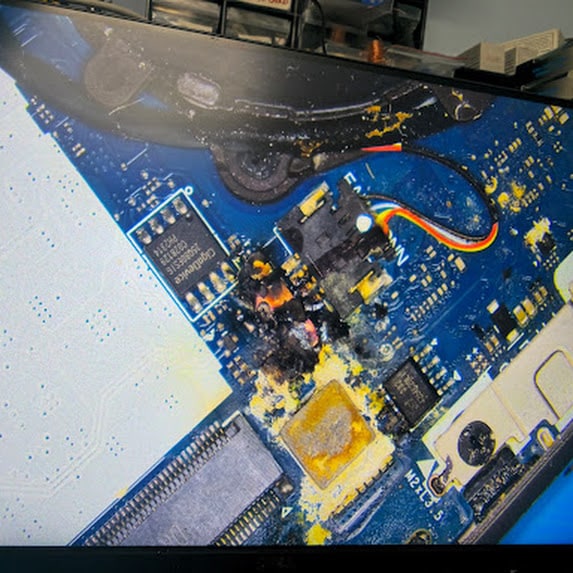 Liquid residue and corrosion on a laptop motherboard before repair