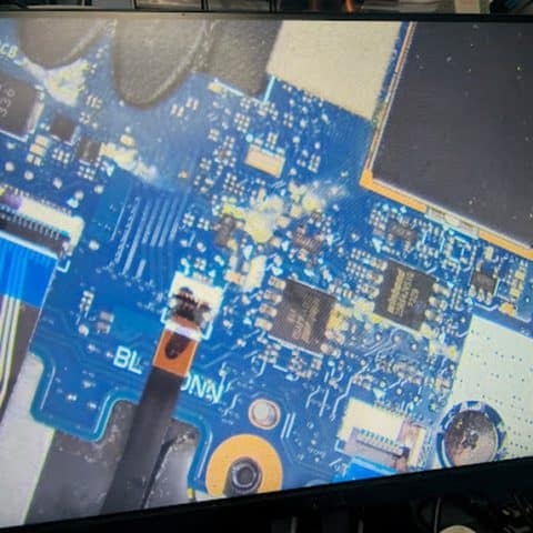 Spill residue between components on a laptop motherboard seen on the microscope screen