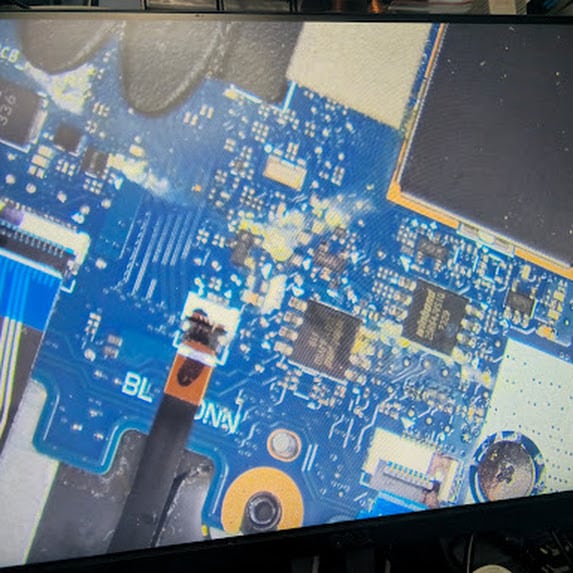Spill residue between components on a laptop motherboard seen on the microscope screen