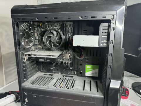 Open desktop PC case with dust on the cooler, the graphics card and the bottom of the case
