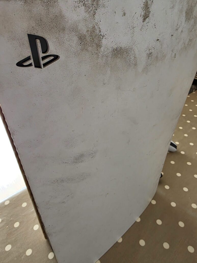 White PlayStation 5 cover with dark grey staining on the outside before the repair