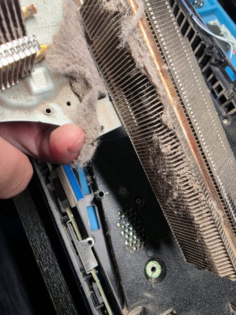 PS5 heatsink held in hand with the fins clogged with dust