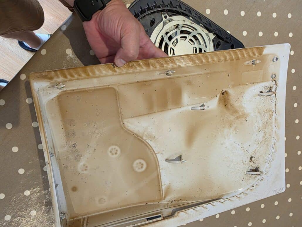 Inside of the PS5 white side panel covered in yellow-brown oily residue mixed with dust